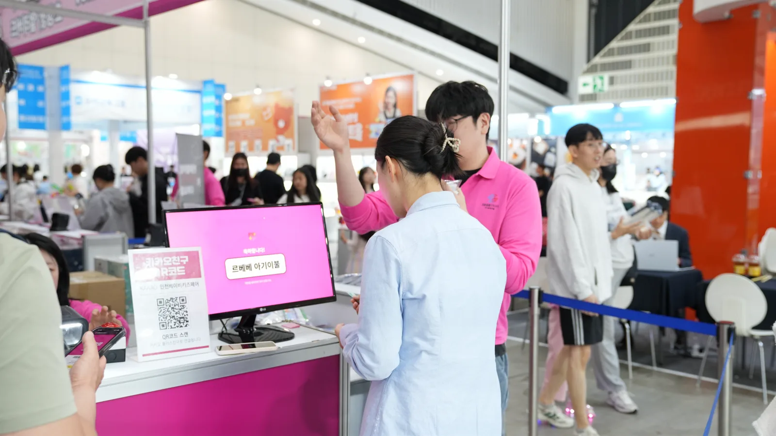 분홍색 운영 스태프가 모니터로 럭키드로우 당첨 결과를 안내하는 현장